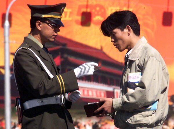 A policeman checks a man's identification on the street in Beijing, China on Sept. 29, 1999. (Stephen Shaver/AFP via Getty Images)