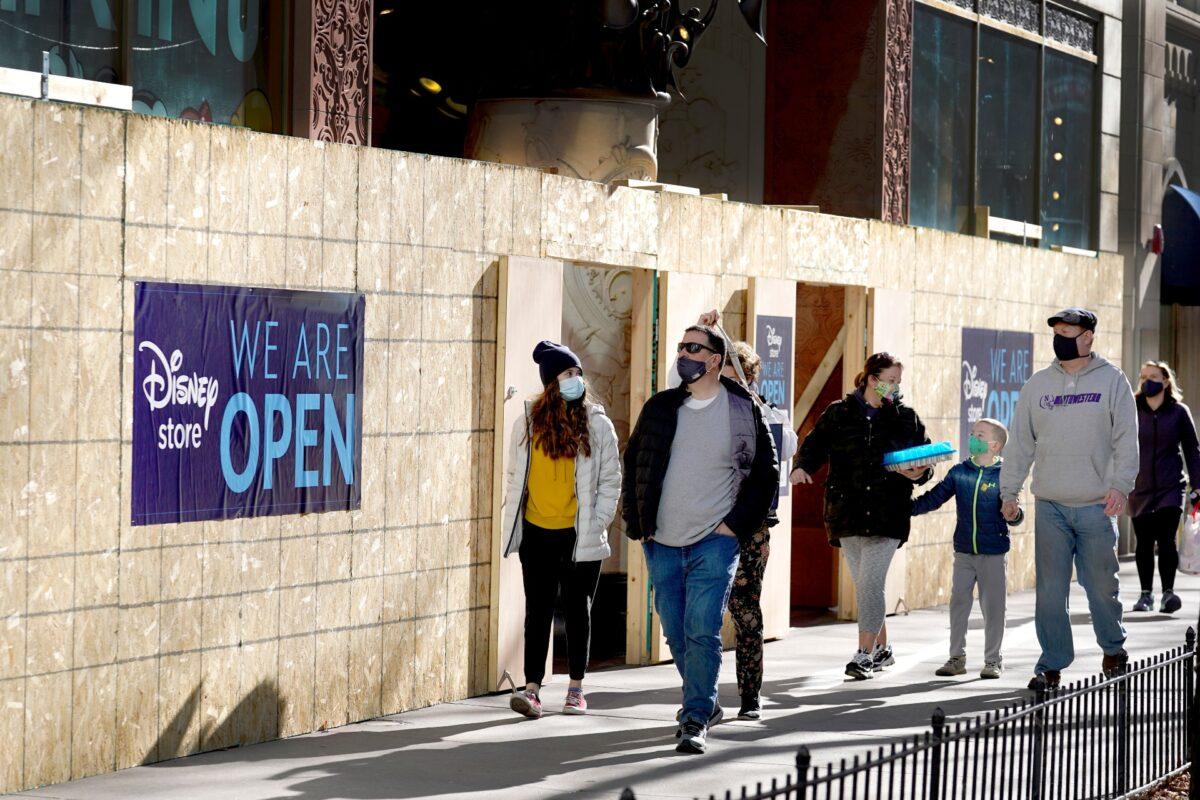  Shoppers pass an open Disney Store that is still partially boarded up from recent vandalism on Chicago's famed Magnificent Mile shopping district in Chicago, Ill., on Nov. 28, 2020. (Charles Rex Arbogast/AP Photo)