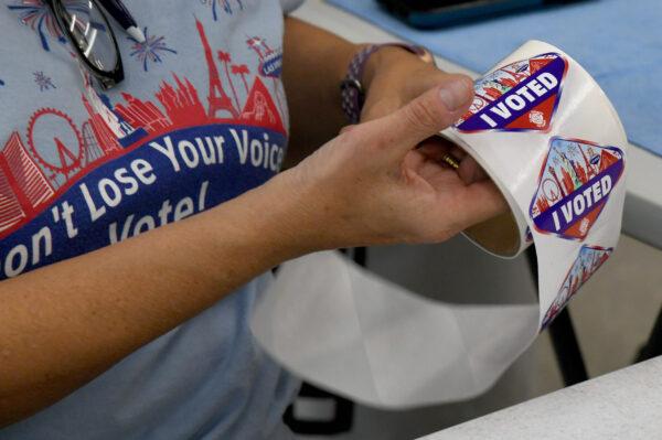 A poll worker unrolls Las Vegas Strip-themed "I Voted" stickers for voters at a polling place at the Veterans Memorial Leisure Center in Las Vegas, Nevada, on Nov. 3, 2020. (Ethan Miller/Getty Images)