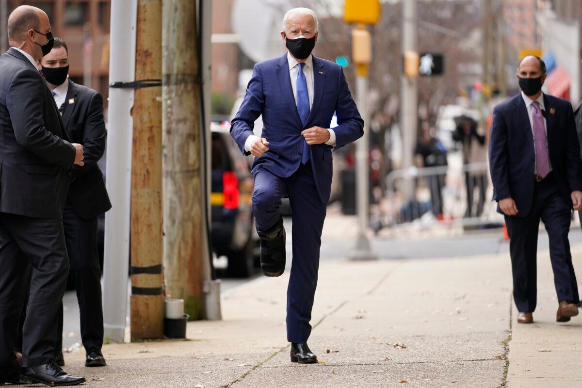 Democratic presidential candidate Joe Biden raises a leg while wearing a walking boot, as he arrives at the Queen Theater in Wilmington, Del., on Dec. 1, 2020. (Andrew Harnik/AP Photo)