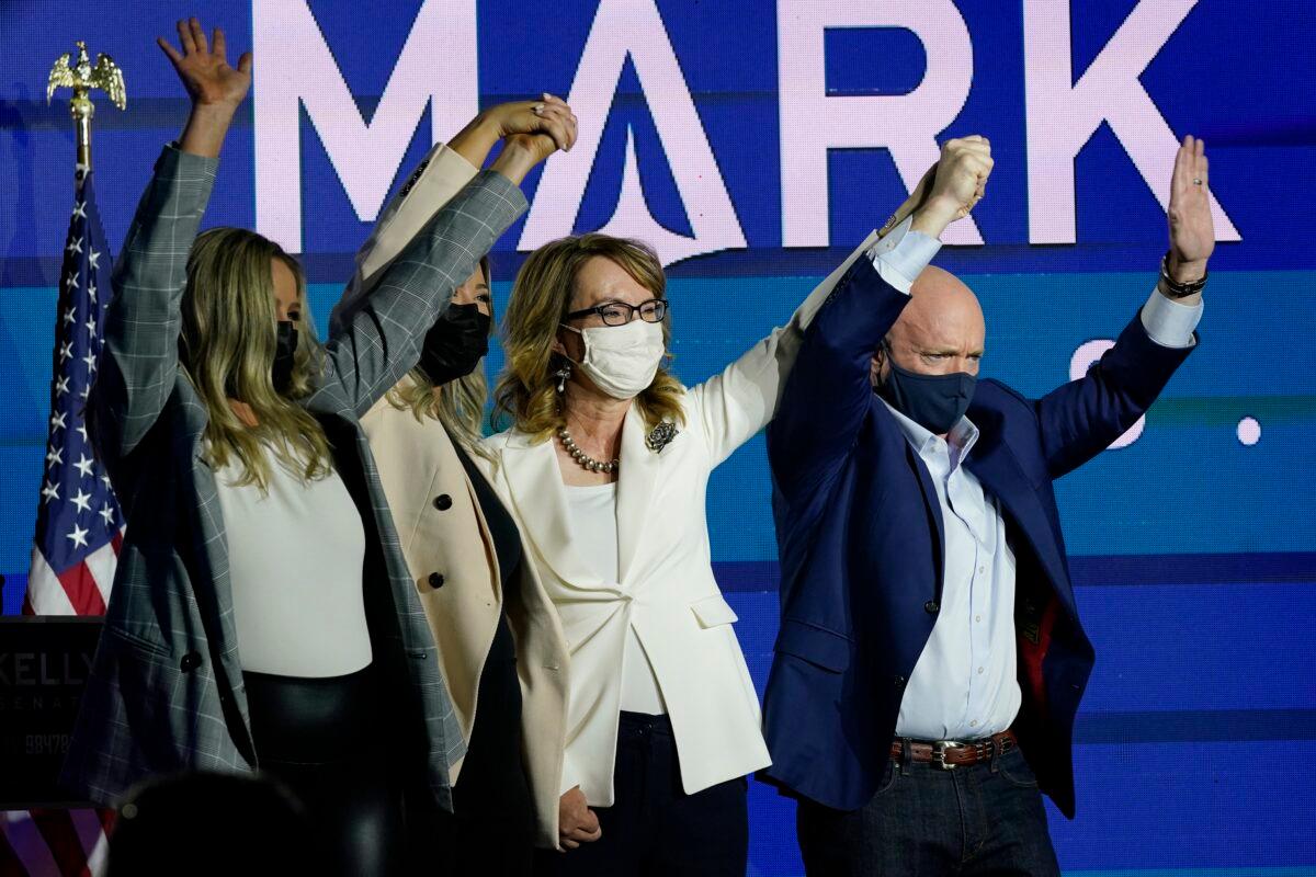 Mark Kelly, right, Arizona Democratic candidate for U.S. Senate, waves to supporters along with his wife Gabrielle Giffords, second from right, and daughters, Claire Kelly, left, and Claudia Kelly, second from left, during an election night event in Tucson, Ariz., on Nov. 3, 2020. (Ross D. Franklin/AP Photo)