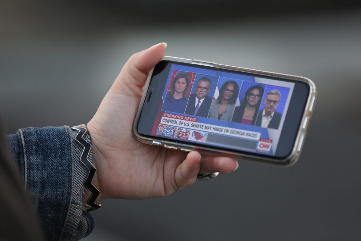 A person watches CNN on her phone in Wilmington, Delaware, on Nov. 6, 2020. (Joe Raedle/Getty Images)