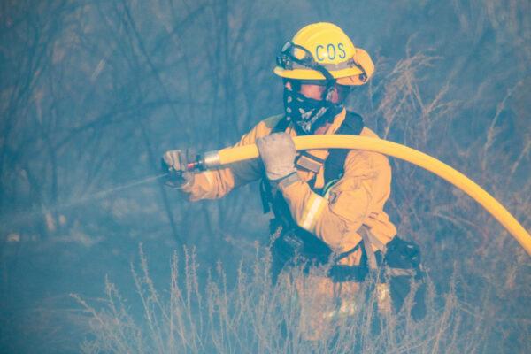 A firefighter sprays water on the Bond Fire in Orange County, Calif., on Dec. 3, 2020. (John Fredricks/The Epoch Times)