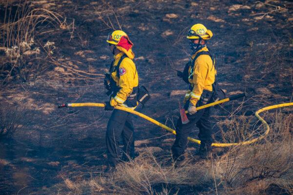 Firefighters hold a hose and a hatchet as they battle the Bond Fire in Silverado Canyon, Calif., on Dec. 3, 2020. (John Fredricks/The Epoch Times)