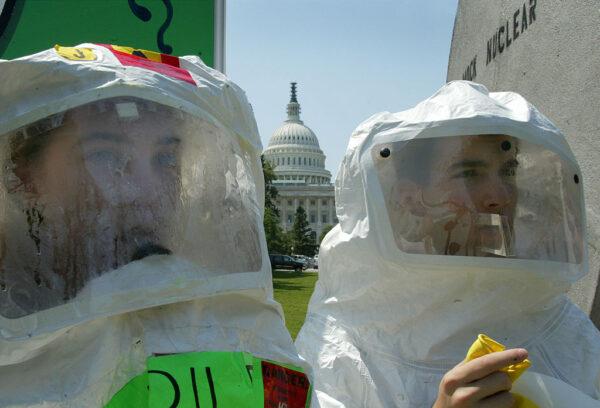 Protesters dressed in protective clothing stand in front of a mock nuclear waste cask, in opposition to a proposal to bury nuclear waste in Nevada’s Yucca Mountain, on Capitol Hill in Washington, D.C., on June 18, 2002. (Mark Wilson/Getty Images)