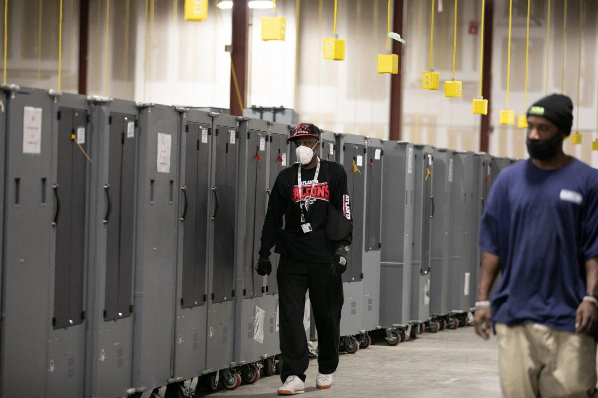Fulton County employees walk among voting machine transporters being stored at the Fulton County Election Preparation Center, in Atlanta, Ga., on Nov. 4, 2020. (Jessica McGowan/Getty Images)