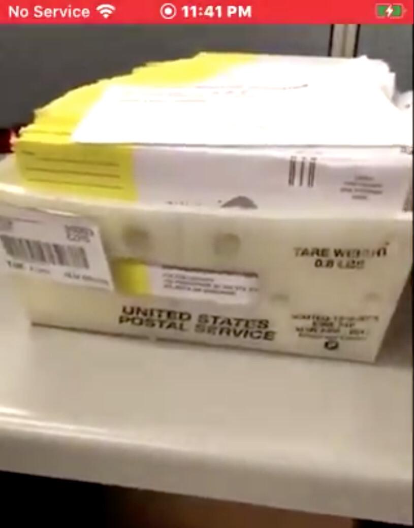 A screenshot of a video posted by Ruby Freeman on Facebook shows a box of ballots in her cubicle. The first ballot doesn't show a return address. (Screenshot/Epoch Times)