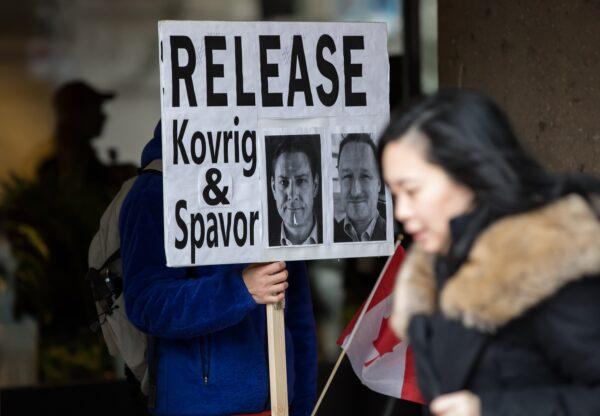 A man holds a sign bearing photographs of Michael Kovrig and Michael Spavor, who have been detained in China, in Vancouver on Jan. 21, 2020. (Darryl Dyck/The Canadian Press)
