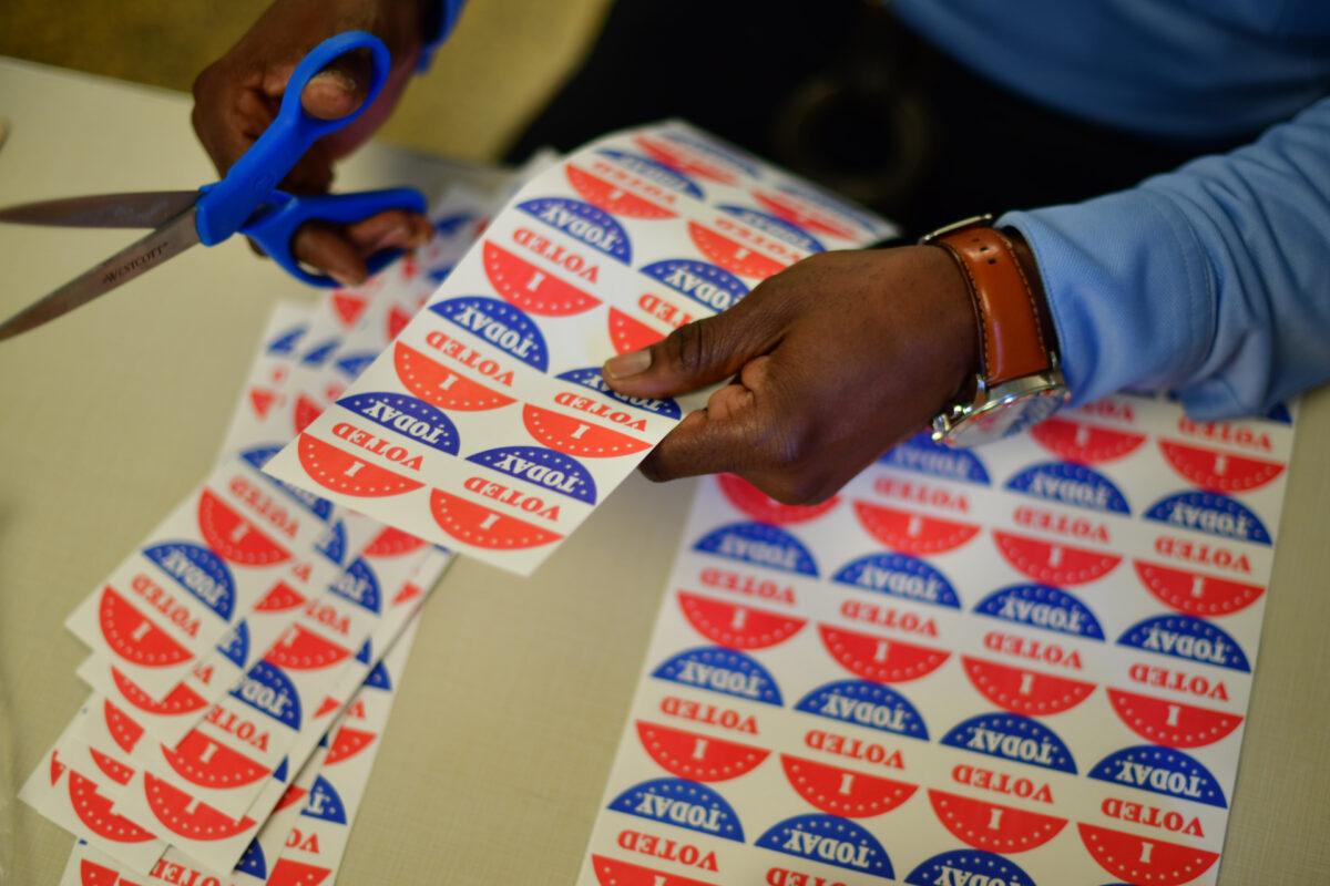 A volunteer cuts out " I VOTED TODAY" stickers for voters lined up outside a satellite polling station in Philadelphia, Pa., on Oct. 27, 2020. (Mark Makela/Getty Images)