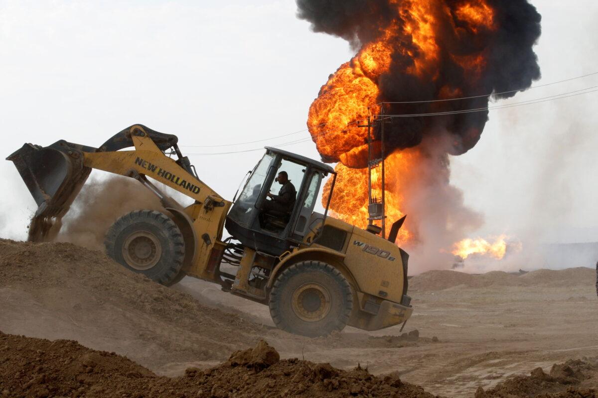 A machine operates as oil wells burn inside the Khabbaz oilfield after they were bombed on the outskirts of Kirkuk, Iraq, on Dec. 9, 2020. (Ako Rasheed/Reuters)