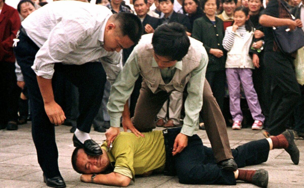 Plainclothes police detain a Falun Gong protester in Tiananmen Square as a crowd watches in Beijing in this Oct. 1, 2000 photo. (AP Photo/Chien-min Chung)