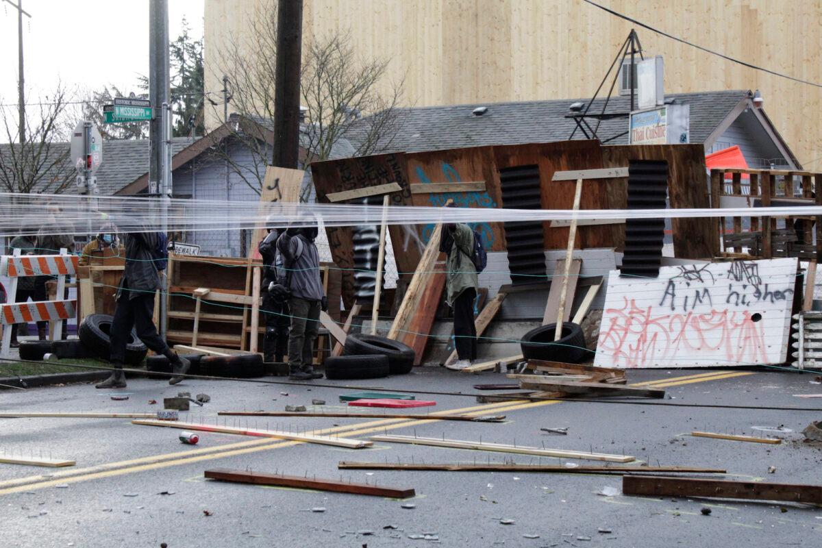 Protesters stand behind barricades at their encampment outside a home in Portland, Ore., on Dec. 9, 2020. (Gillian Flaccus/AP Photo)