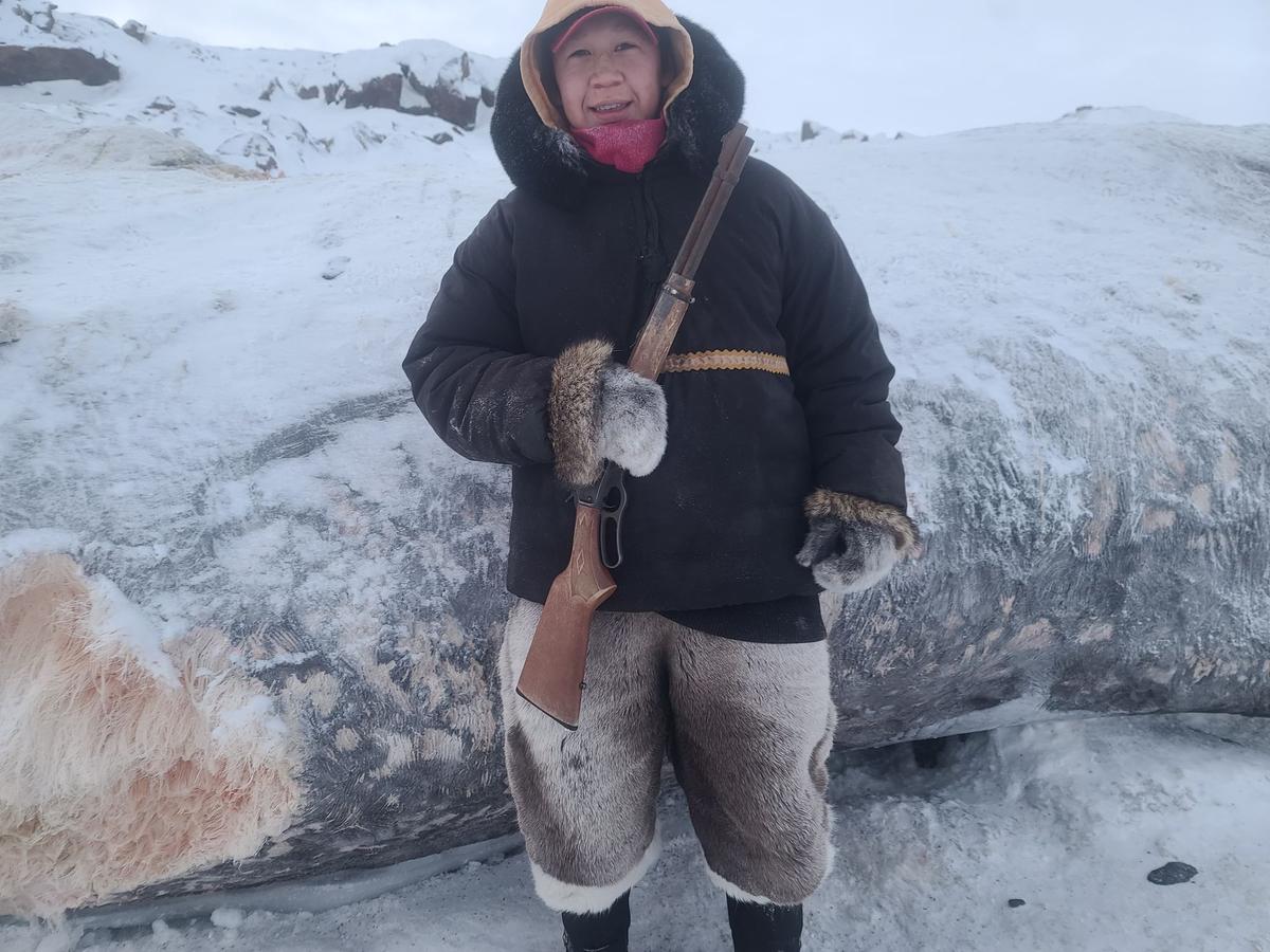 Lenny Panigayak's nephew, Andrew Panigayak, poses with his rifle in front of the bowhead whale carcass. (Courtesy of <a href="https://www.facebook.com/lenny.panigayak">Lenny Panigayak</a>)