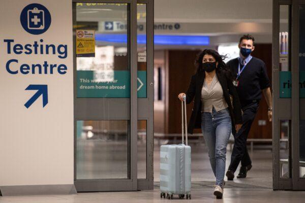 A passenger walks past a sign directing people to a CCP virus testing site adjacent to Terminal 1 of Manchester Airport in Manchester, northern England on Dec. 3, 2020. (Oli Scarff/AFP via Getty Images)