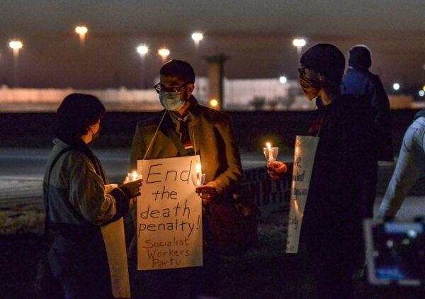 Gabby Prosser, left, and Nick Neeser, right, from Minneapolis, Minn., talk with Samir Hazboun, center, from Louisville, Ky., during a protest against the execution of Brandon Bernard across Prairieton Road from the Federal Death Chamber in Terre Haute, Ind., on Dec. 10, 2020. (Austen Leake/The Tribune-Star via AP)