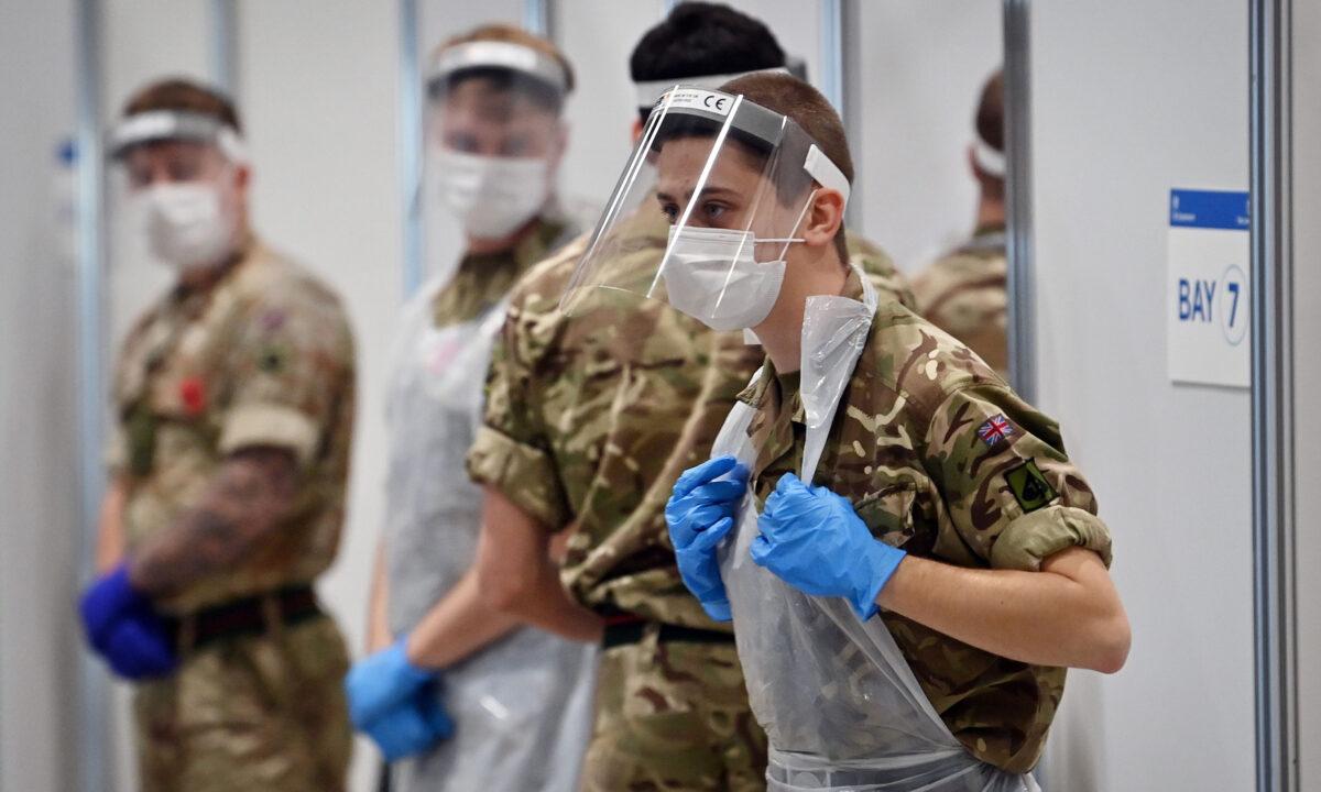 Soldiers wearing full PPE in the form of face shields, gloves, masks, and bibs wait to assist CCP virus testing at a rapid testing centre in the Liverpool Exhibition Centre in Liverpool, England, on Nov. 11, 2020 (Paul Ellis/AFP via Getty Images)