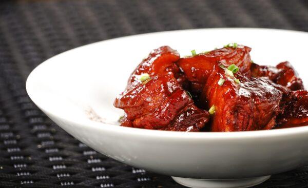 Dong po pork, chunks of braised pork belly in a dark, thin sauce. (NASDAQ chives/Shutterstock)