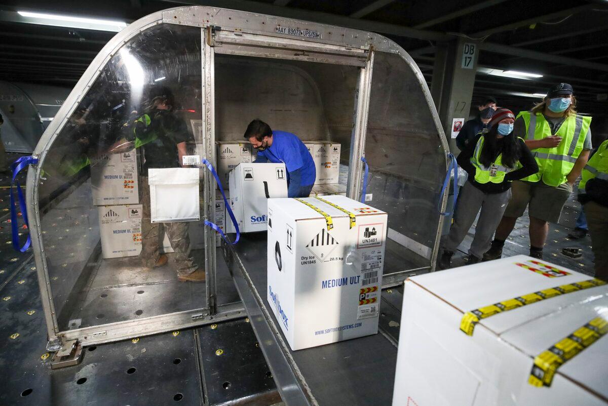 Boxes containing the first shipments of the Pfizer and BioNTech COVID-19 vaccine are unloaded from air shipping containers at UPS Worldport in Louisville, Ky., on Dec. 13, 2020. (Michael Clevenger/Pool/Getty Images)