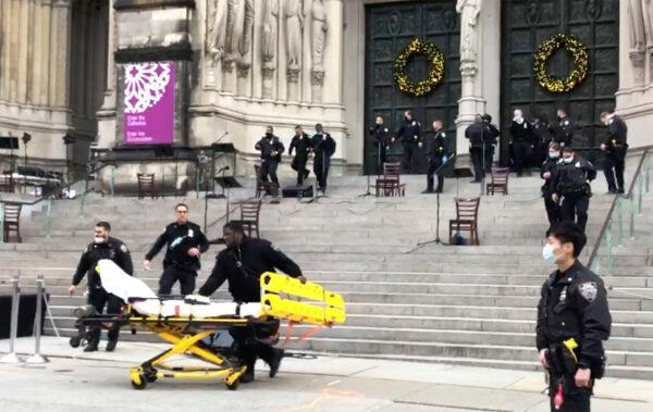 Emergency medical personnel pull a stretcher up to the scene of a shooting at the Cathedral Church of St. John the Divine in New York City on Dec. 13, 2020. (AP Photo/Ted Shaffrey)