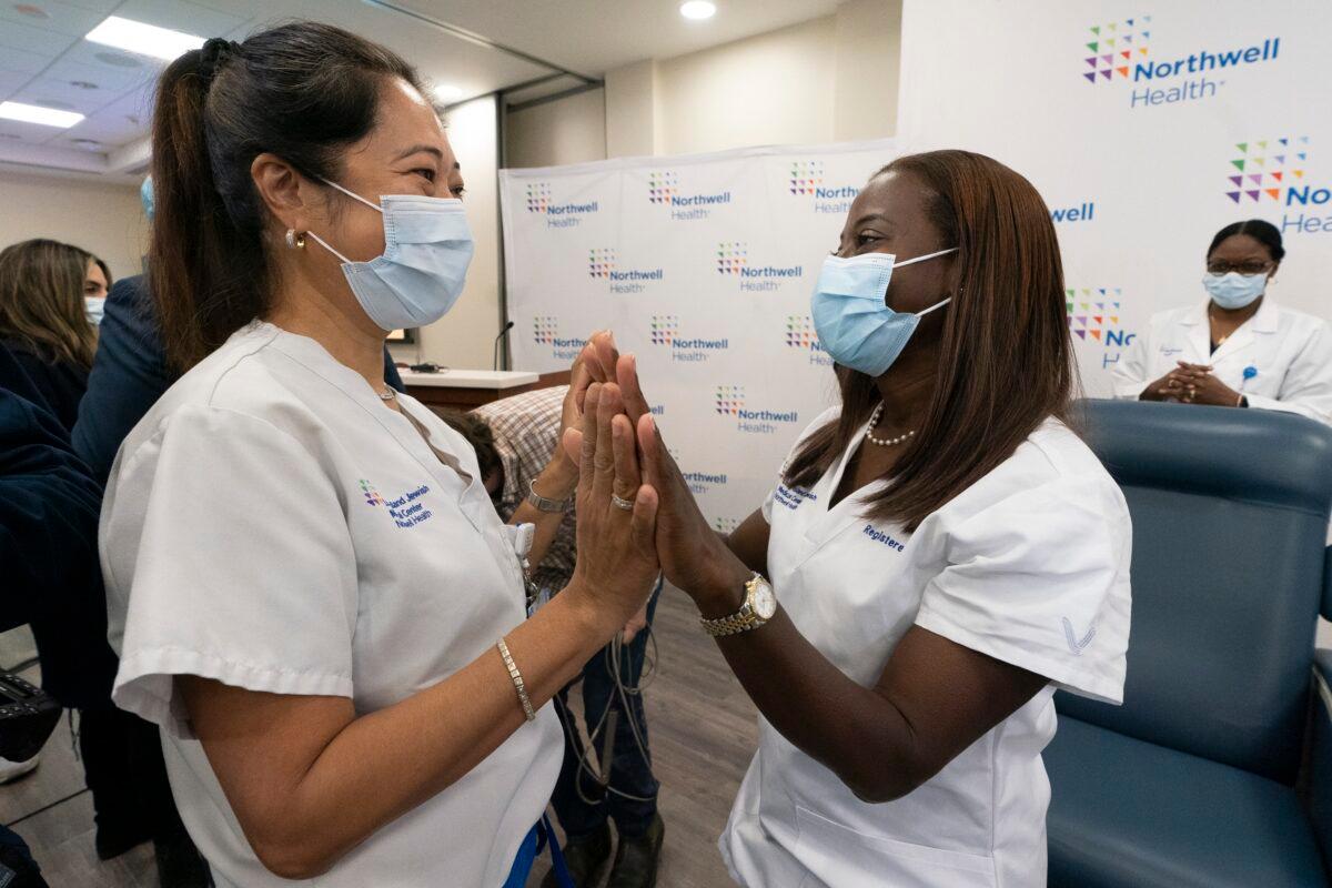 Nurse Annabelle Jimenez, left, congratulates nurse Sandra Lindsay after she is inoculated with the Pfizer-BioNTech COVID-19 vaccine at Long Island Jewish Medical Center, in the Queens borough of New York, on Dec. 14, 2020. (Mark Lennihan/Pool/AP Photo)