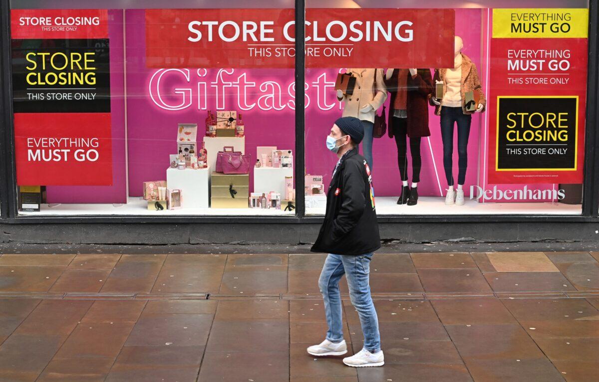  A pedestrian wearing a face mask walks past "Store Closing" signs in the window display of a Debenhams store in Manchester, northern England, on Dec. 2, 2020. (Paul Ellis/AFP via Getty Images)