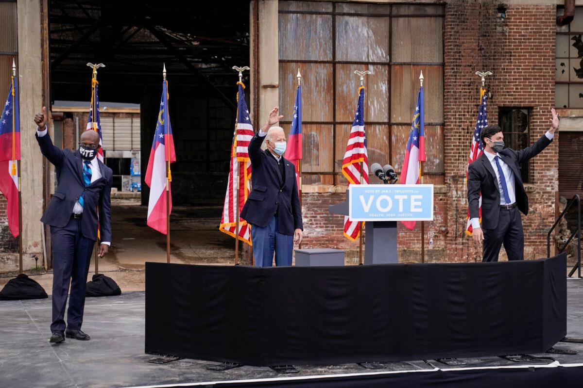 Flanked by U.S. Democratic Senate candidates Rev. Raphael Warnock (L) and Jon Ossoff (R), Democratic presidential nominee Joe Biden gestures to the crowd at the end of a drive-in rally at Pullman Yard in Atlanta, Ga., on Dec. 15, 2020. (Drew Angerer/Getty Images)
