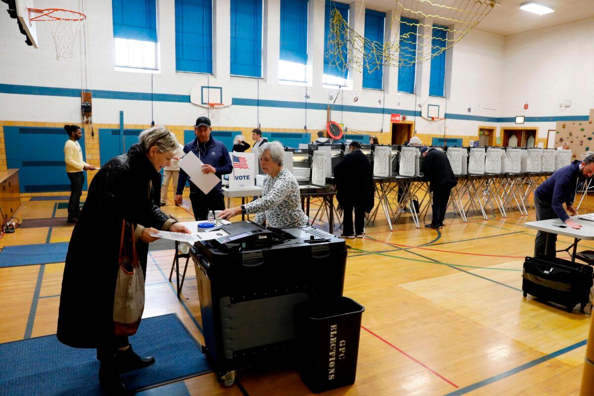 People put ballots in a tabulation machine in Grosse Pointe, Mich., in a March 10, 2020, file photograph. (Jeff Kowalsky/AFP via Getty Images)