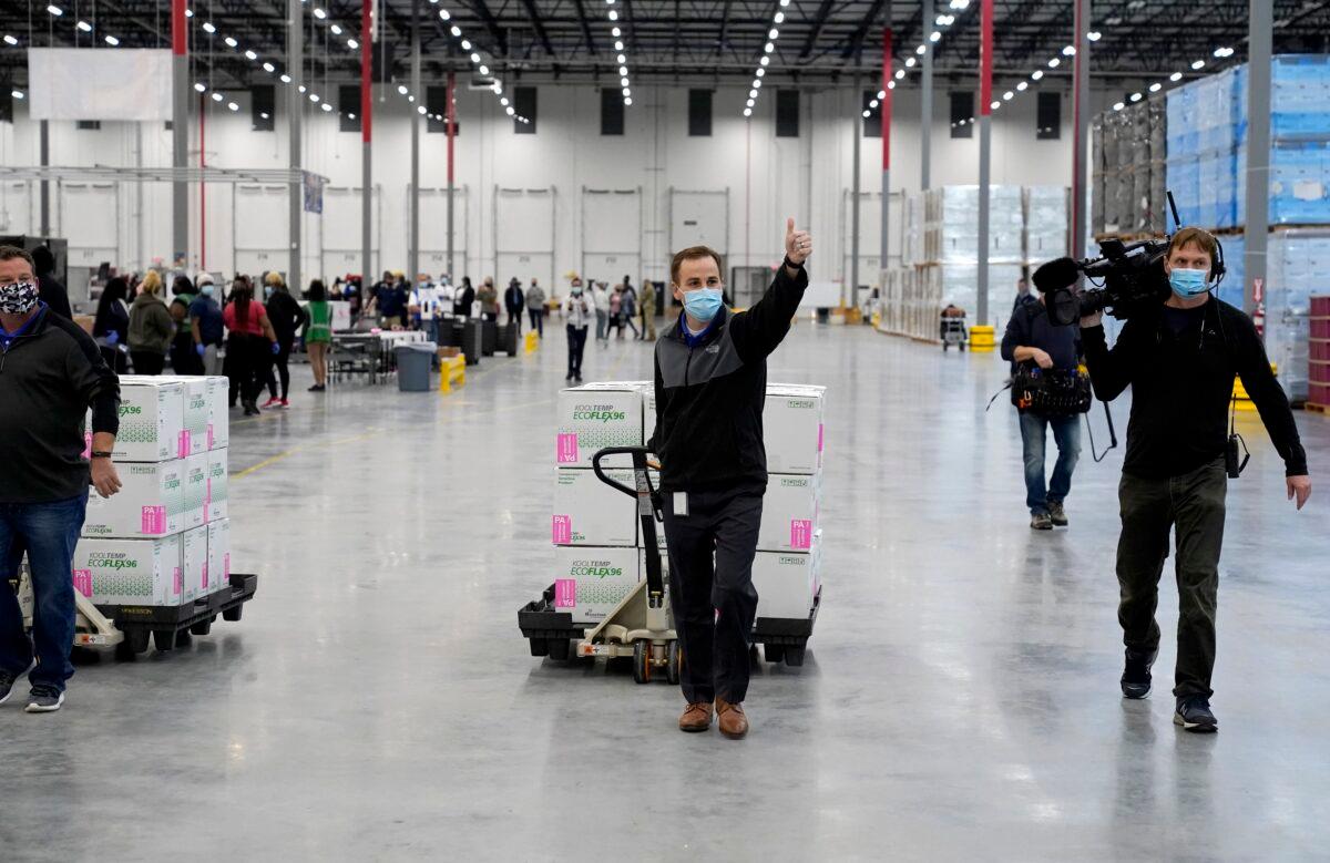 A worker gives a thumbs up while transporting boxes containing the Moderna COVID-19 vaccine to the loading dock for shipping at the McKesson distribution center in Olive Branch, Miss., on Dec. 20, 2020. (Paul Sancya/Pool/AP Photo)