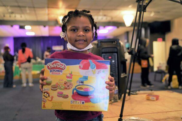 Chloe, 5, holds a gift she received through Ruby's Roses charity event in Chicago, on Dec. 19, 2020. (Cara Ding/The Epoch Times)