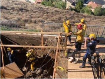 Workers stand over a hole where a man was killed when a wall of dirt buried him in the City of Orange, Calif., on Dec. 19, 2020. (Courtesy of the City of Orange Fire Department)