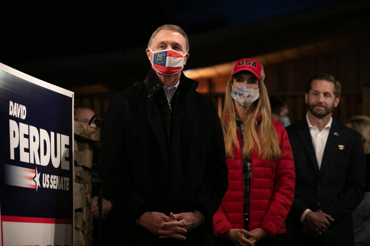 Sens. David Perdue (R-Ga.), left, and Kelly Loeffler (R-Ga.) stand during a rally in Cumming, Ga., on Dec. 20, 2020. (Jessica McGowan/Getty Images)