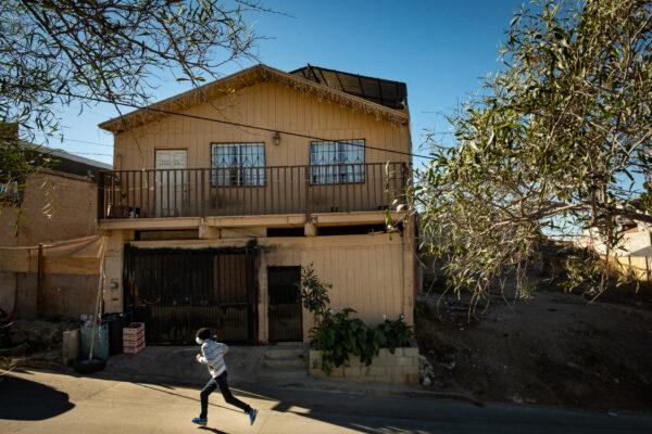 A man runs past Casas De Dios foster home in Tijuana, Mexico, on Dec. 19, 2020. (John Fredricks/The Epoch Times)