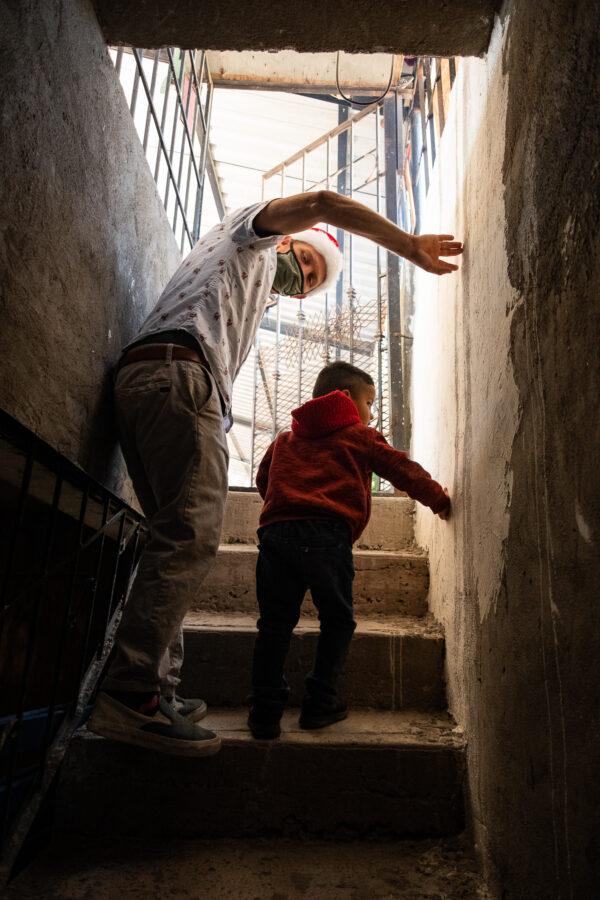 Volunteer Logan Muchow helps a small boy at Casas De Dios foster home in Tijuana, Mexico, on Dec. 19, 2020. (John Fredricks/The Epoch Times)