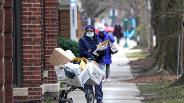 A U.S. Postal Service worker delivers packages, boxes, and letters along her route in the Hyde Park neighborhood of Chicago on Dec. 22, 2020. (Charles Rex Arbogast/AP Photo)