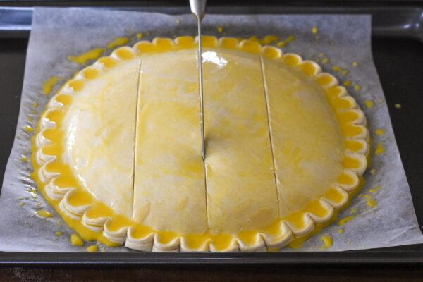 Brush the whole galette with egg wash and score a design into the top. (Audrey Le Goff)