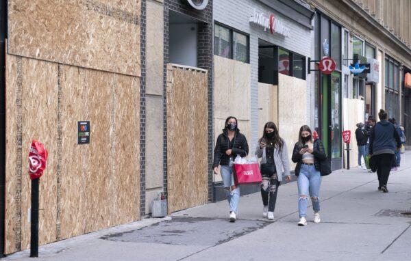 People walk past boarded-up stores on Saint-Catherine Street in Montreal on June 3, 2020. (The Canadian Press/Paul Chiasson)
