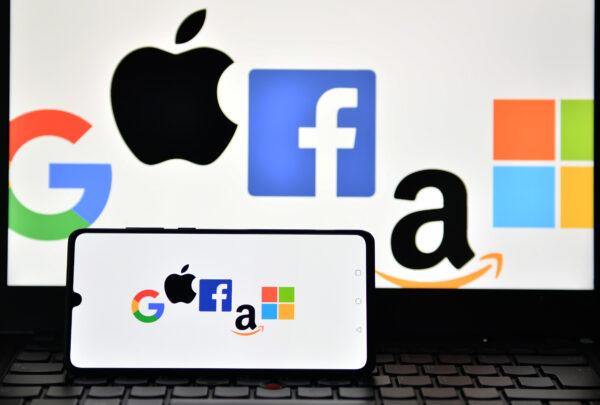 The logos of Google, Apple, Facebook, Amazon, and Microsoft are displayed on a mobile phone and a laptop screen in London on Dec. 18, 2020. (Justin Tallis/AFP via Getty Images)