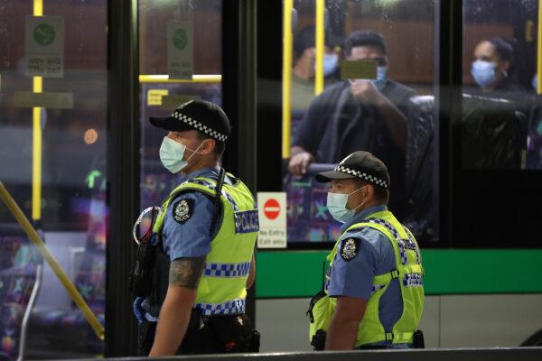 Passengers from Qantas flight QF583 are escorted to waiting Transperth buses by Police Officers after being processed following their arrival at Perth Airport. (Paul Kane/Getty Images)