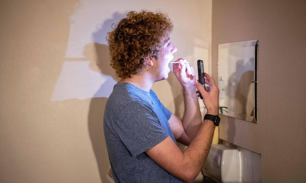 A student performs a university-provided CCP virus lateral flow test on himself in his college room in Oxford, England, on Dec. 12, 2020. (Laurel Chor/Getty Images)