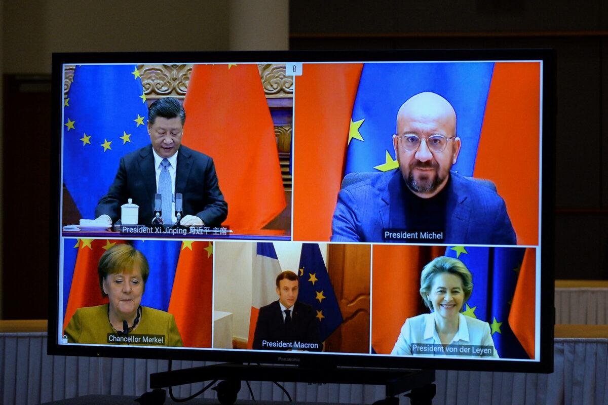 European Commission President Ursula von der Leyen, European Council President Charles Michel, German Chancellor Angela Merkel, French President Emmanuel Macron, and Chinese leader Xi Jinping are seen on a screen during a video conference, in Brussels, on Dec. 30, 2020. (Johanna Geron/Pool/Reuters)