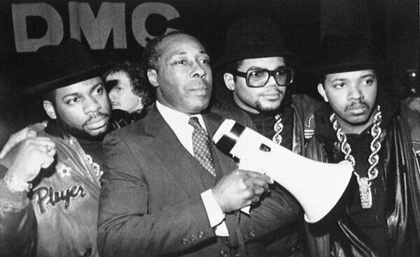 Joe Clark, principal of Eastside High School, stands with rap group Run-DMC before the group gave a concert at the school in support of Clark's way of running his school in Paterson, N.J., on Feb. 11, 1988. (Peter Cannata/AP Photo)