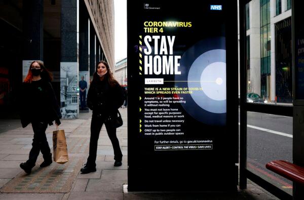 Commuters walk past a bus stop with a government message about COVID-19 tier 4 restrictions urging people to stay home, in London, on Dec. 29, 2020. (Tolga Akmen/AFP via Getty Images)