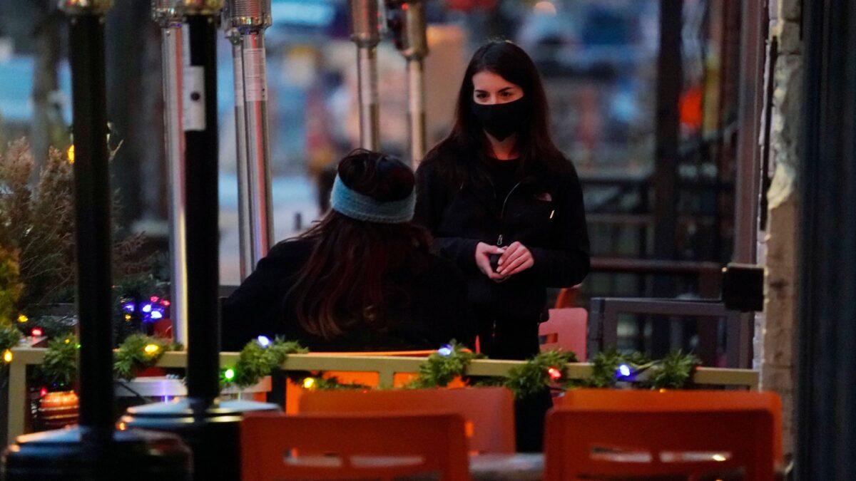  An employee tends to a patron sitting in the outdoor patio of a sushi restaurant in downtown Denver, on Dec. 28, 2020. (David Zalubowski/AP Photo)