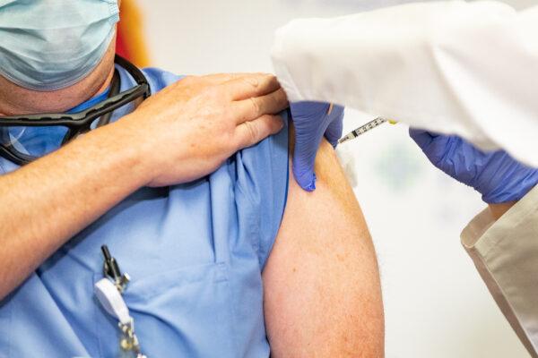 A nurse recieves a COVID-19 vaccination at St. Joseph Hospital in Orange, Calif., on Dec. 16, 2020. (John Fredricks/The Epoch Times)