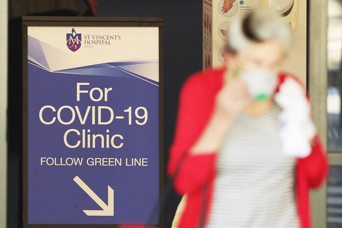  People pass signs for a COVID-19 Clinic as they enter or exit St Vincent's hospital in Sydney, Australia on March 18, 2020. (Mark Metcalfe/Getty Images)