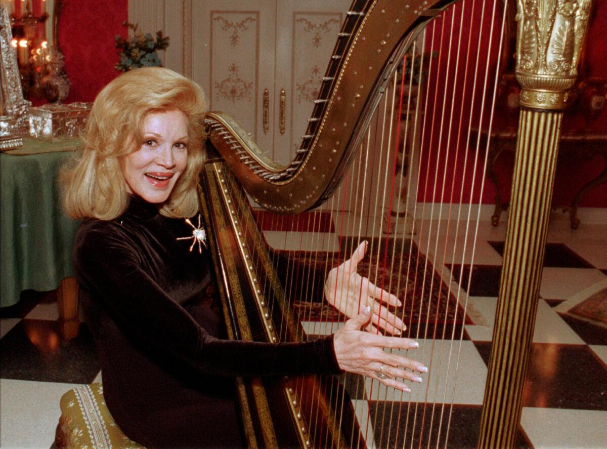 In this Dec. 12, l995 file photo, Phyllis McGuire, the youngest of The McGuire Sisters, plays a harp at her home in Las Vegas. (Lennox McLendon/AP Photo, File)