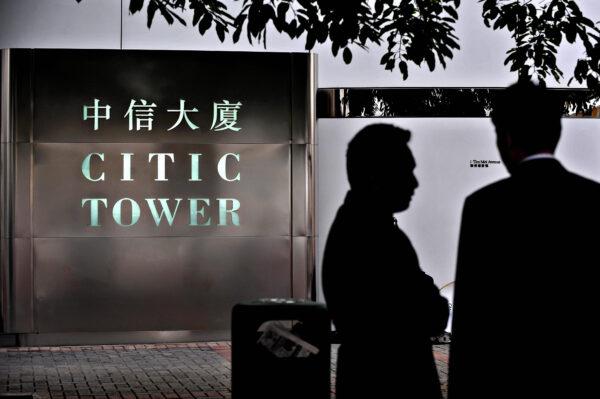 Two men chat next to the offices of CITIC Pacific in Hong Kong on April 8, 2009. (Philippe Lopez/AFP via Getty Images)