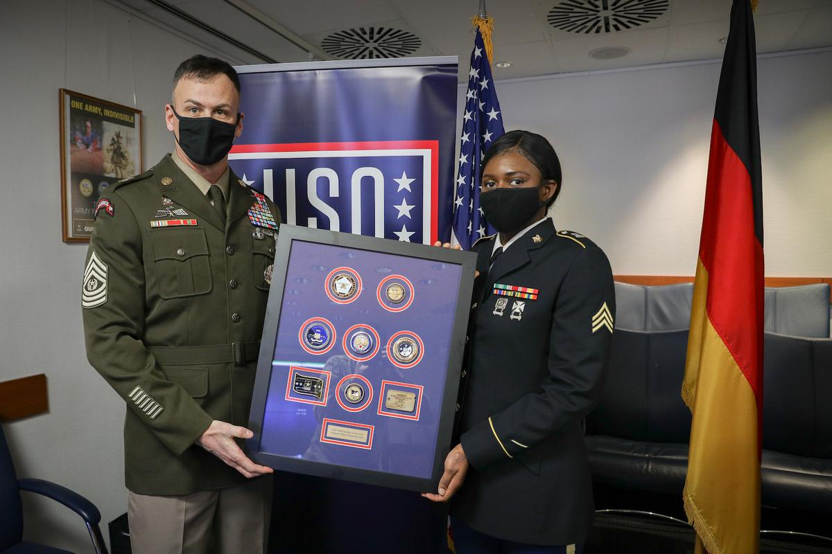 U.S. Army Command Sgt. Maj. Sean Howard and U.S. Army Sgt. Mary Ehiarinmwian of the 21st Theater Sustainment Command holding the USO Soldier of the Year plaque in Kaiserslautern, Germany, on Dec. 15, 2020 (<a href="https://www.dvidshub.net/image/6457636/sgt-mary-ehiarinmwian-2020-uso-soldier-year">Spc. Katelyn Myers</a>/U.S. Army)