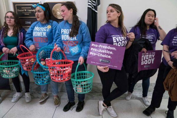 Members of Students for Life of America hold baskets of baby socks representing abortions alongside abortion rights activists from NARAL Pro-Choice America as they demonstrate outside of Rep. Dan Lipinski's office in Washington, D.C., on March 4, 2020. (Sarah Silbiger/Getty Images)