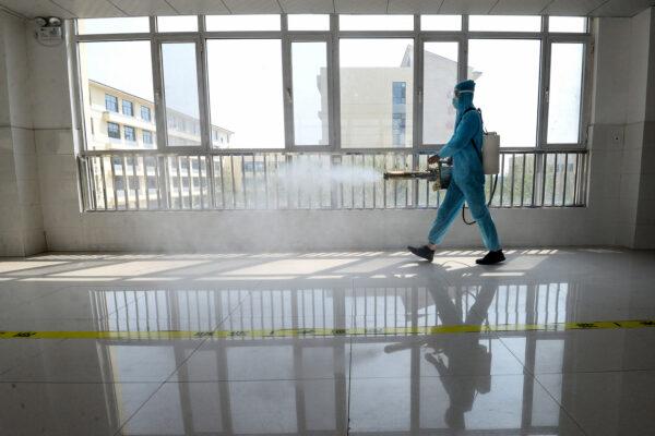 A staff member wearing protective gear spraying disinfectant in a classroom in Handan city, Hebei Province, China, on Aug. 30, 2020. (STR/AFP via Getty Images)